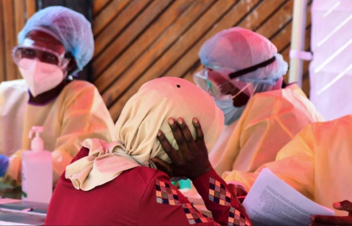A woman holding her head while waiting for her results to the health worker.